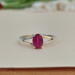 Puede incluir: Un anillo de plata con una piedra preciosa de color rosa intenso de corte ovalado sujeta por cuatro garras. La banda tiene un dise&ntilde;o de v&aacute;stago dividido que se estrecha hacia la piedra, creando un aspecto limpio para esta joya con gema central.