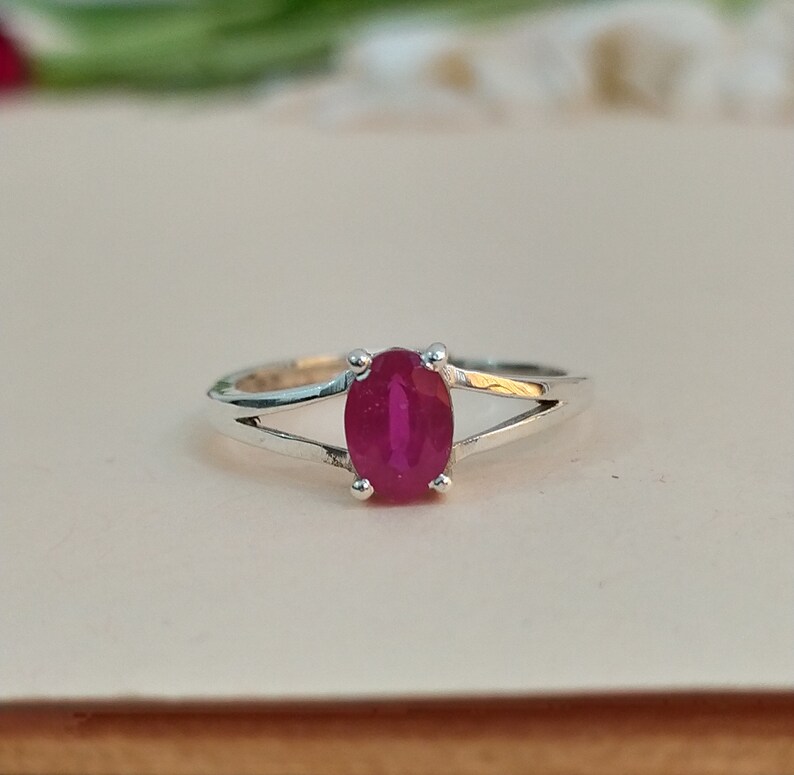Puede incluir: Un anillo de plata con una piedra preciosa de color rosa intenso de corte ovalado sujeta por cuatro garras. La banda tiene un dise&ntilde;o de v&aacute;stago dividido que se estrecha hacia la piedra, creando un aspecto limpio para esta joya con gema central.