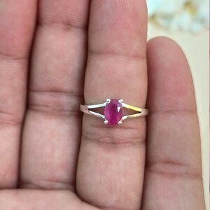 Puede incluir: Un anillo de plata con una piedra preciosa de color rosa rojizo vibrante y corte ovalado, sujeta por cuatro garras. La banda tiene un dise&ntilde;o dividido que se estrecha hacia la piedra, creando una apariencia elegante y pulida para esta joya.