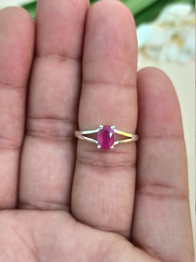 Puede incluir: Un anillo de plata con una piedra preciosa de color rosa rojizo vibrante y corte ovalado, sujeta por cuatro garras. La banda tiene un dise&ntilde;o dividido que se estrecha hacia la piedra, creando una apariencia elegante y pulida para esta joya.
