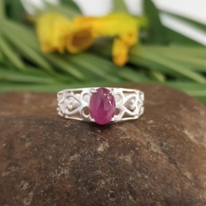 以下が含まれることがあります： 繊細なフィリグリーのデザインにセットされたピンクの楕円形の宝石が付いたシルバーリング