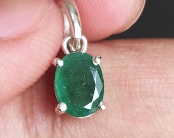 May include: A silver pendant with a green oval emerald gemstone.