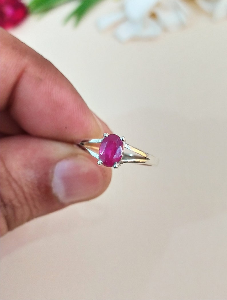 Puede incluir: Un anillo de plata con una piedra preciosa de rub&iacute; rosa intenso de corte ovalado, sujeta por un engaste de cuatro garras. La banda del anillo es de plata pulida y presenta un dise&ntilde;o dividido que se estrecha al llegar al engaste.