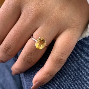 May include: A silver ring with a large oval-shaped yellow gemstone.