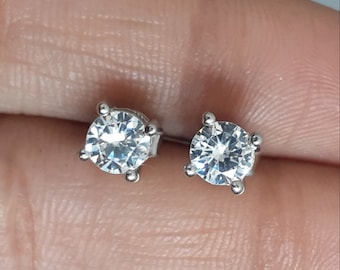 May include: A pair of silver stud earrings with clear round cubic zirconia stones.