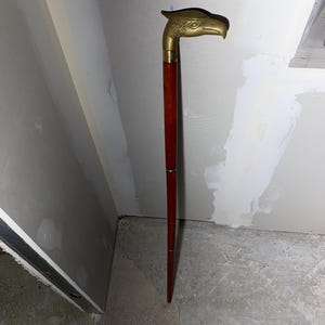May include: A wooden walking stick with a gold eagle head handle.