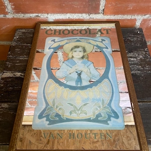 May include: Framed vintage advertisement for Van Houten chocolate. The artwork features a child in a sailor suit within a blue and gold decorative frame. The word "CHOCOLAT" is at the top, and "VAN HOUTEN" is at the bottom.