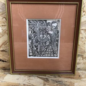 May include: Framed black and white print depicting a historical scene with figures in a detailed interior setting. The print is set within a brown mat and a gold-trimmed brown wooden frame, creating a classic aesthetic.