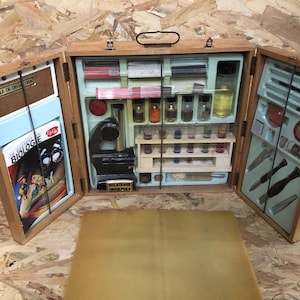May include: Open wooden vintage biology kit with a microscope, vials, and tools. The kit is open, revealing various scientific instruments and a book titled "Biologie". The kit is on a wooden surface.