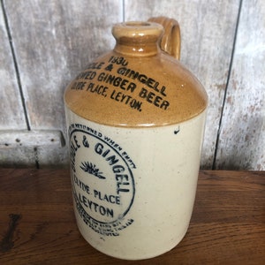Könnte beinhalten: Eine braune und weiße Keramikflasche für Ingwerbier mit einem blauen und weißen Etikett, auf dem steht: "1930 Cole & Gingell Gebrautes Ingwerbier Clyde Place, Leyton. Bei Leerung zurückgeben Cole & Gingell Clyde Place Leyton Gebühr für Gläser, aber nur bei Verwendung dieses Glases wird verfolgt"