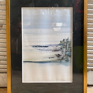 May include: A framed watercolour painting of a seascape with a city skyline in the background. The painting is in shades of blue, grey, and white, with a few touches of black. The artist's signature is visible in the bottom right corner.