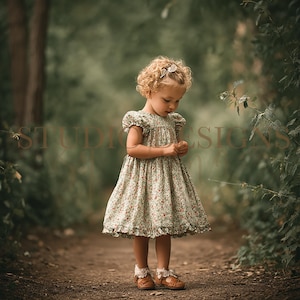 Könnte beinhalten: Ein junges Kind trägt ein Kleid mit Blumenmuster, Rüschensaum und kurzen Ärmeln auf einem Feldweg. Das Kleid ist hellgrün mit kleinen roten Blumen. Sie trägt braune Lederschuhe mit weißer Spitzentrimmung und eine Haarschleife.