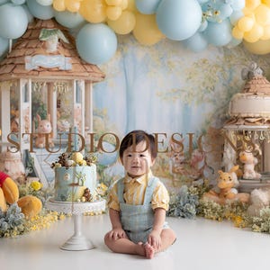 Puede incluir: Una escena caprichosa con un niño vestido de amarillo y azul, rodeado de globos, peluches y estructuras decorativas. Un pastel con decoraciones temáticas de bosque se encuentra sobre un soporte blanco. El telón de fondo es un mural forestal.