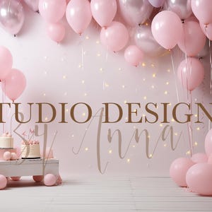 May include: A pink and white birthday cake with the words "Studio Designs by Anna" on a white background with pink balloons.