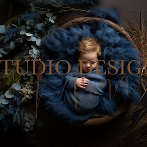 May include: A sleeping baby in a blue knitted wrap, nestled in a woven basket with blue and brown dried floral accents. The text "STUDIO DESIGNS" is superimposed on the image.