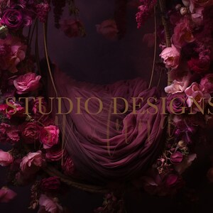 May include: A purple fabric hammock hangs from a floral wreath made of pink and purple flowers. The wreath is suspended against a dark purple background. The text "STUDIO DESIGNS" is visible in the center of the image.