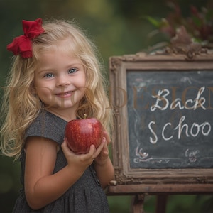 May include: A young child with blonde hair and a red bow holds a red apple. A chalkboard with the words "Back to School" is in the background. The child is wearing a gray dress.