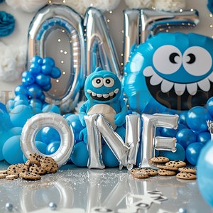 Könnte beinhalten: Ein blauer und silberner 'EIN' Ballonbogen mit blauen Ballons und einem blauen Monsterballon. Auf dem Boden liegen auch Kekse.