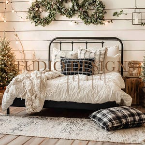 May include: A cozy bedroom scene with a black metal bed frame, adorned with white bedding and decorative pillows. A black and white plaid pillow rests on the floor. Two small Christmas trees and a rug complete the holiday decor. Wreaths and string lights add to the festive atmosphere.