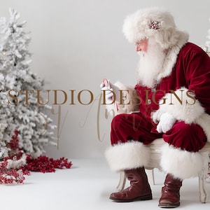 Puede incluir: Papá Noel con un traje de terciopelo rojo con ribetes de piel blanca, sentado en una silla blanca. Sostiene un bastón de caramelo. Los árboles de Navidad nevados y las bayas rojas decoran el fondo. El texto "STUDIO DESIGNS" es visible.