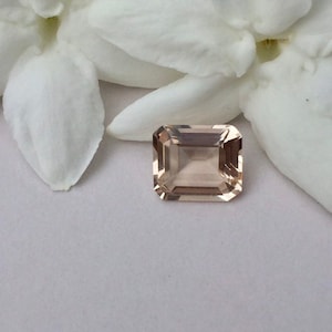 May include: A light pink, rectangular, faceted gemstone with a smooth, polished finish.