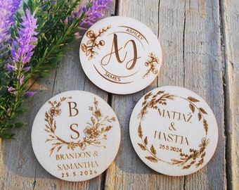 May include: Three round wooden signs with floral designs and engraved text. The first sign says "Ashley James" with the initials "AJ" in a cursive font. The second sign says "Brandon & Samantha 25.5.2024" with the initials "BS". The third sign says "Matjaz & Nastja 25.5.2024".