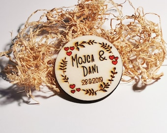 May include: A round wooden sign with a floral wreath design. The sign is decorated with red hearts and the text "MOJCA & DANI 28.9.2019".