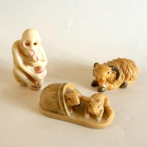 May include: Ivory-colored figurines of a monkey, a ram, and two mice. The monkey sits with its knees bent, holding a peach. The ram has curved horns and a textured coat. The mice are nestled in a bed-like structure.