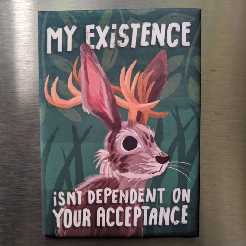 May include: A green background with a cartoon illustration of a rabbit with antlers. The rabbit has brown fur, a white nose, and large black eyes. The text "MY EXISTENCE ISN'T DEPENDENT ON YOUR ACCEPTANCE" is written in white letters on the image.