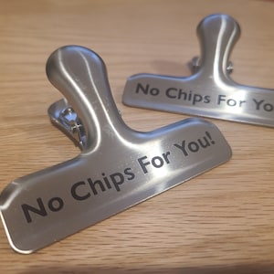 May include: Two silver metal chip clips with the text "No Chips For You!" engraved on them.