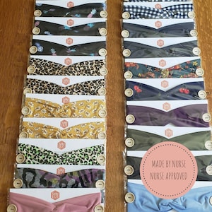 May include: A collection of colorful headbands with different patterns, including pineapple, leopard print, floral, and camouflage. The headbands are made of soft fabric and have a button on each side. The text "MADE BY NURSE NURSE APPROVED" is visible on a pink circle.
