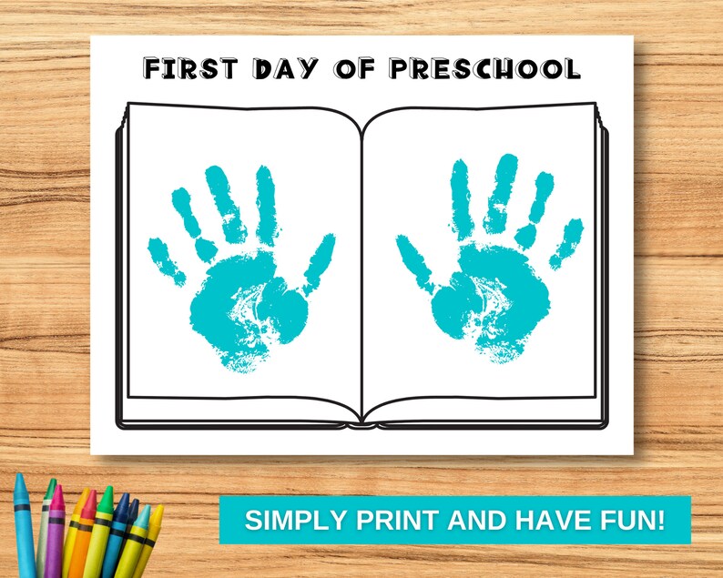 May include: A printable coloring page featuring an open book with the text "FIRST DAY OF PRESCHOOL" at the top. The book has two blank spaces for handprints, with the text "SIMPLY PRINT AND HAVE FUN!" at the bottom.