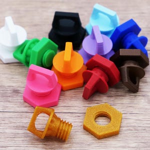K&ouml;nnte beinhalten: Eine Sammlung farbenfroher, 3D-gedruckter Flaschenverschl&uuml;sse und eine sechseckige Mutter. Die Verschl&uuml;sse sind in verschiedenen Farben erh&auml;ltlich, darunter Wei&szlig;, Schwarz, Gr&uuml;n, Orange, Pink, Rot, Braun, Gold, Lila und Blau. Die Verschl&uuml;sse haben einen Griff zum einfachen Entfernen.