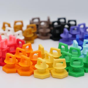 K&ouml;nnte beinhalten: Eine Sammlung farbenfroher Flaschenverschl&uuml;sse aus Kunststoff, kreisf&ouml;rmig angeordnet. Die Verschl&uuml;sse sind in verschiedenen Farben erh&auml;ltlich, darunter Rot, Orange, Gelb, Gr&uuml;n, Blau, Lila, Schwarz, Braun, Rosa und Wei&szlig;. Jeder Verschluss hat ein einzigartiges Design.
