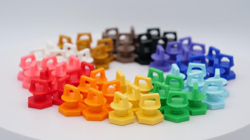 K&ouml;nnte beinhalten: Eine Sammlung farbenfroher Flaschenverschl&uuml;sse aus Kunststoff, kreisf&ouml;rmig angeordnet. Die Verschl&uuml;sse sind in verschiedenen Farben erh&auml;ltlich, darunter Rot, Orange, Gelb, Gr&uuml;n, Blau, Lila, Schwarz, Braun, Rosa und Wei&szlig;. Jeder Verschluss hat ein einzigartiges Design.