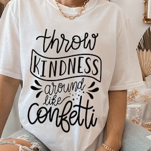 Könnte beinhalten: Weißes T-Shirt mit schwarzem Text, der "Throw Kindness Around Like Confetti" lautet.