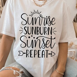 May include: White t-shirt with black text that reads "Sunrise Sunburn Sunset Repeat".