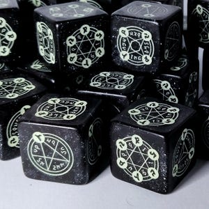 Op de afbeelding: Een verzameling zwarte dobbelstenen met oplichtende witte symbolen. Elke dobbelsteen heeft een pentagram en andere esoterische symbolen. De dobbelstenen zijn vierkant en hebben een gespikkelde textuur. Perfect voor tabletop games.
