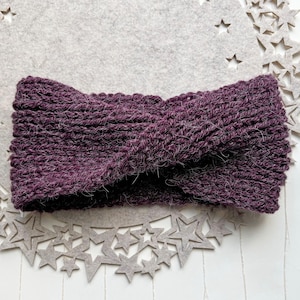 Könnte beinhalten: Ein violettes Strick Stirnband mit einem gedrehten Design. Das Stirnband ist aus einem weichen, flauschigen Garn.