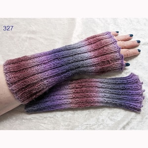 Könnte beinhalten: Ein Paar fingerlose Strickhandschuhe in Lila, Grau und Rosa mit gerippter Struktur. Die Handschuhe werden auf dem Arm einer Person gezeigt.