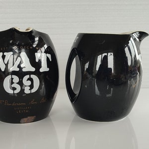 Può includere: Due brocche in ceramica nera. Una brocca ha un'etichetta bianca con il testo "VAT 69" e "W. Sanderson & Son Ltd. Distillers Leith".
