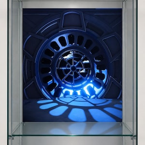 Könnte beinhalten: Eine Vitrine mit einem blauen, kreisförmigen, futuristischen Design an der Rückwand. Das Design wirft einen blauen Schatten auf den Boden der Vitrine. Die Vitrine hat Glasböden und -seiten sowie ein Licht oben.
