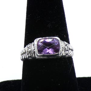 May include: A silver ring with a square-shaped amethyst gemstone. The ring has a textured band.