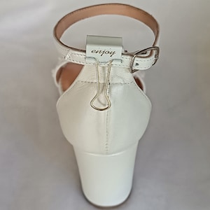 White leather handmade block heel sandal with a block heel and ankle strap. The heel is approximately 2 inches high.