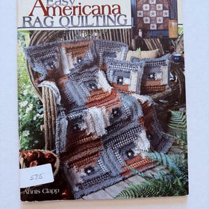 May include: A book titled "Easy Americana Rag Quilting" with a cover featuring a rag quilt on a chair. The quilt is in shades of brown, gray, and blue, with star accents. The book also shows a basket of apples.