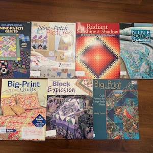 May include: A collection of quilting books with titles including "Disappearing Nine-Patch Quilts," "Nine-Patch Pictures," and "Big-Print Quilts." The books feature colorful quilt designs and patterns, with text and images on the covers.