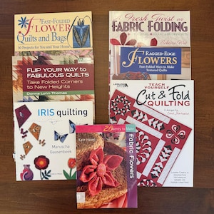 May include: A collection of quilting and fabric craft books. Titles include "Fast-Folded Flower Quilts and Bags", "Flip Your Way to Fabulous Quilts", "Iris Quilting", "A Fresh Twist on Fabric Folding", "Ragged-Edge Flowers", "Teach Yourself Cut & Fold Quilting", and "Fabric Flowers".