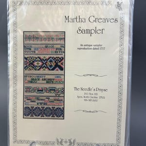 May include: A white card with a cream colored border featuring a reproduction of an antique sampler from 1717. The sampler is titled "Martha Greaves Sampler" and features a colorful cross-stitch design with the text "Good Grace to you are orits for your Martha Greaves" and "Fthouseest Chel D Grace amongst thou have place". The card also includes the text "The Needle's Prayse" and contact information for the company.