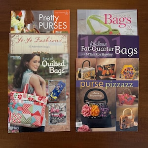 May include: A collection of books about purses and bags. Titles include "Pretty Purses", "Yo-Yo Fashions", "Best of Quilted Bags", "The Book of Bags", "101 Fabulous Fat-Quarter Bags", and "Purse Pizzazz". The books feature colorful designs.