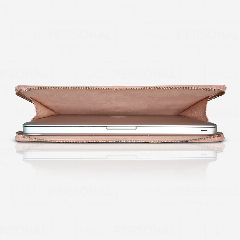 May include: A light pink laptop sleeve with a zippered opening, partially containing a silver laptop. The interior of the sleeve is lined with a matching light pink material, and the exterior features a smooth, solid-coloured finish.